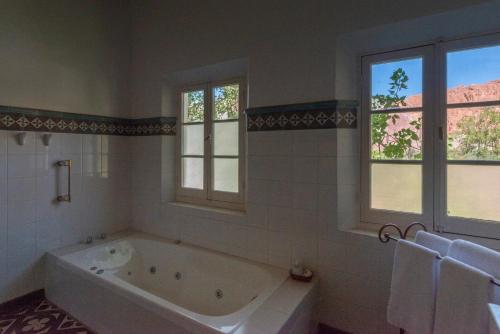 a white bath tub in a bathroom with windows at Hotel El Manantial del Silencio in Purmamarca