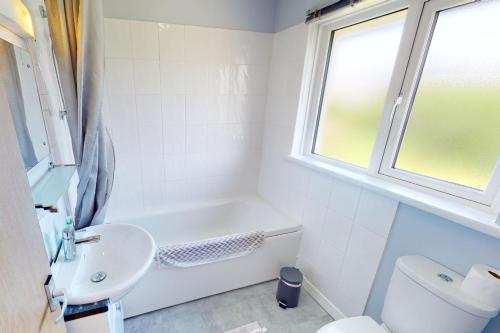 a bathroom with a tub and a sink and a toilet at CROYDE PEACH COTTAGE 3 Bedrooms in Croyde