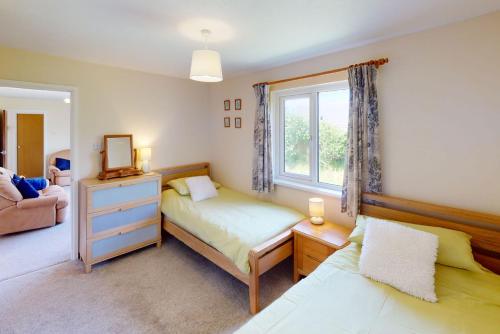 a bedroom with a bed and a dresser and a window at CROYDE PEACH COTTAGE 3 Bedrooms in Croyde
