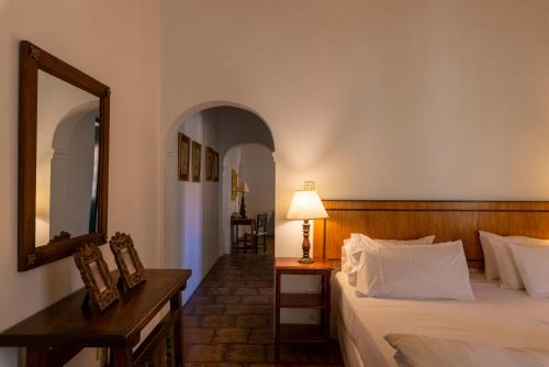 a bedroom with a bed and a mirror and a lamp at Hotel El Manantial del Silencio in Purmamarca
