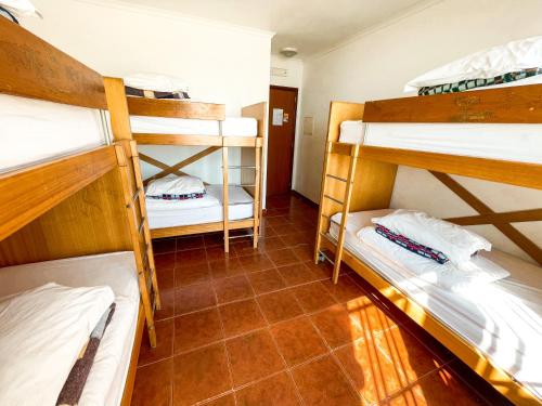 a room with three bunk beds and a tiled floor at HI Areia Branca - Pousada de Juventude in Areia Branca