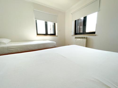 two white beds in a bedroom with two windows at HI Areia Branca - Pousada de Juventude in Areia Branca