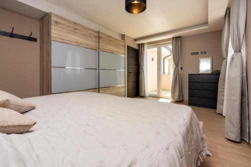 a bedroom with a large white bed and sliding glass doors at DOLLY LUX in Crikvenica