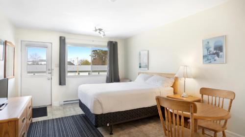 1 dormitorio con cama, mesa y escritorio en Homeport Motel, en Lunenburg