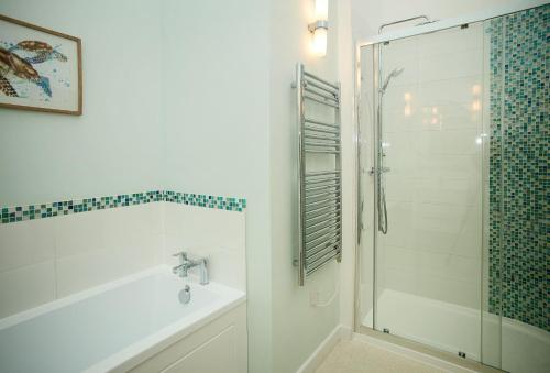 uma casa de banho com um chuveiro, uma banheira e um lavatório. em Evenwood Byre em Kenley