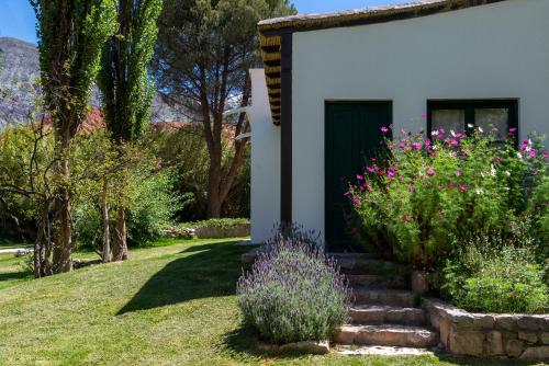 a white house with a green door and some flowers at Hotel El Manantial del Silencio in Purmamarca