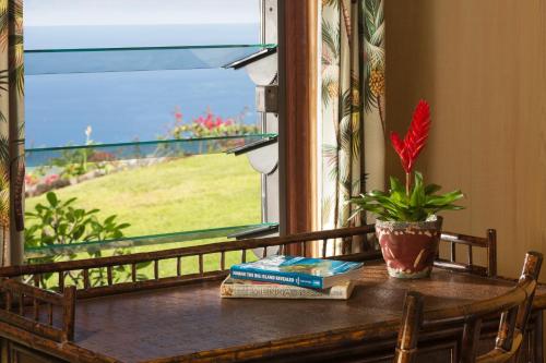 a table with a book and a plant and a window at Holualoa Inn in Kailua-Kona