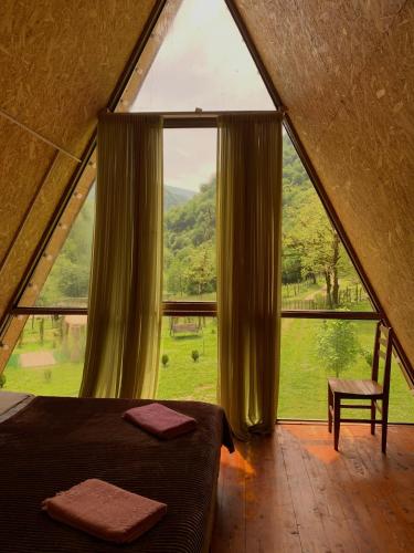 a bedroom with a large window in a tent at Nahei Cottage Martvili in Martvili