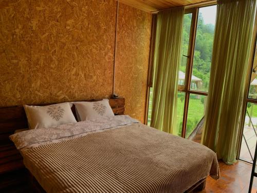 a bedroom with a bed and a large window at nahei cottage in Martvili