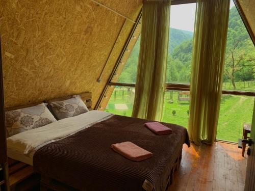 a bed in a room with a large window at nahei cottage in Martvili