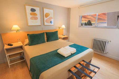 1 dormitorio con 1 cama grande con almohadas verdes en Hotel Plaza Bariloche en San Carlos de Bariloche