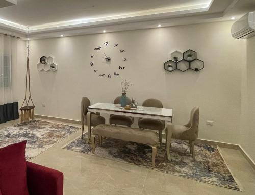 uma sala de jantar com mesa e cadeiras e um relógio na parede em B-Home 2 no Cairo
