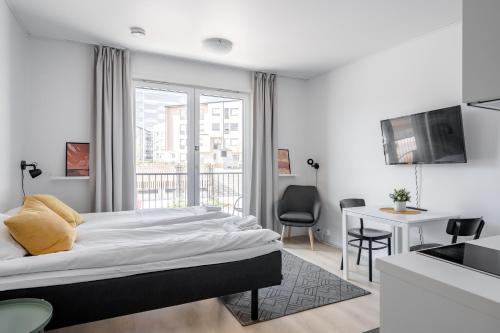 a white bedroom with a large bed and a desk at Hiisi Homes Turku Fleminginkatu in Turku