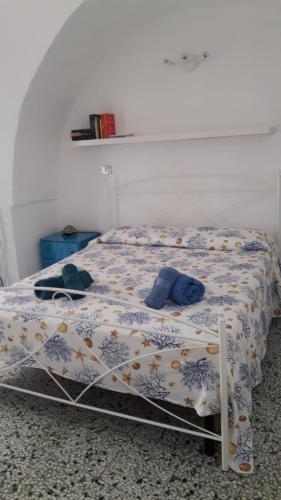 a bed with a comforter and two hats on it at Muri de mainè in Ostuni