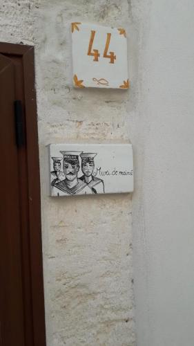 a sign on a wall with a picture of three men at Muri de mainè in Ostuni