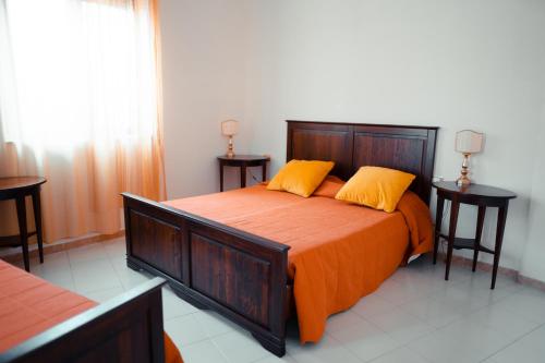 a bedroom with a large bed with orange sheets and yellow pillows at Savoia Residence in Acireale
