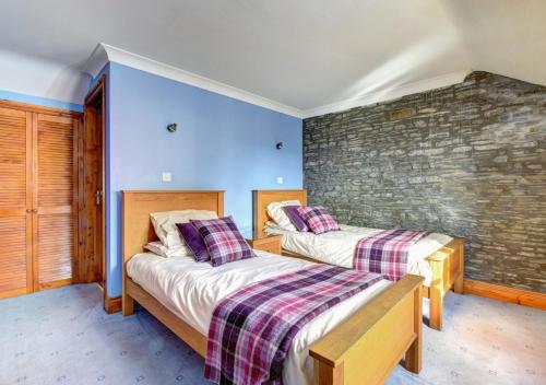2 camas en una habitación con una pared de ladrillo en Hen Ysgubor, en Lampeter