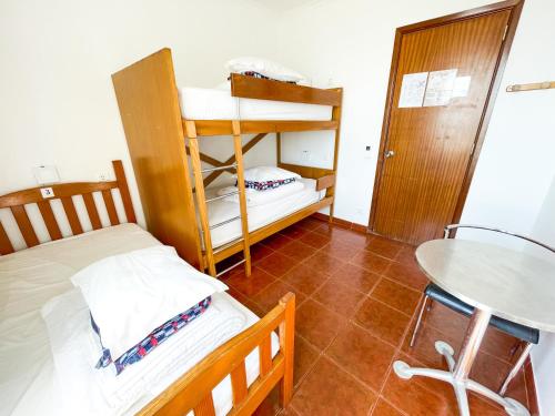a small room with two bunk beds and a table at HI Areia Branca - Pousada de Juventude in Areia Branca
