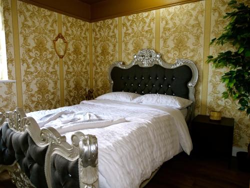 a bedroom with a large bed with white sheets and gold wallpaper at Stunningly Opulent Gold Apartment Near Sheffield FULL SKY TV in Rotherham