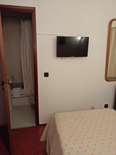 a bedroom with a bed and a flat screen tv on the wall at Hotel Cavaleiros De Cristo in Tomar