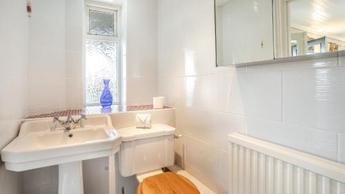 a white bathroom with a sink and a toilet at The Gite in Oystermouth