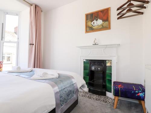a white bedroom with two beds and a fireplace at Meneage House in Helston