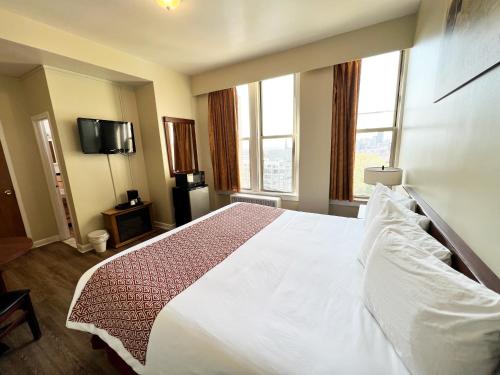 a bedroom with a large white bed and two windows at Lenox Hotel and Suites in Buffalo