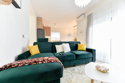 ein Wohnzimmer mit einem grünen Sofa und einem Tisch in der Unterkunft Family apartment Amare in Zadar