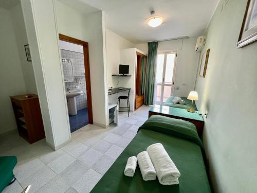 1 dormitorio con 2 camas verdes y escritorio en Hotel Minerva, en Otranto