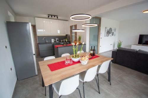 KobdiljにあるHoliday house Oljkaのキッチン、ダイニングルーム(木製テーブル、白い椅子付)
