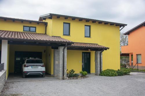 une maison jaune avec une voiture garée dans le garage dans l'établissement Holiday house Oljka, à Kobdilj