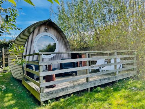 a large wooden dog house in the grass at Armadilla 3 at Lee Wick Farm Cottages & Glamping in Clacton-on-Sea