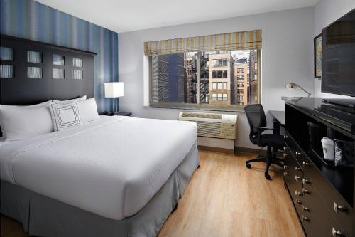 ニューヨークにあるフェアフィールド イン ＆ スイーツ バイ マリオット ニューヨーク マンハッタン / チェルシーのベッド、デスク、窓が備わるホテルルームです。