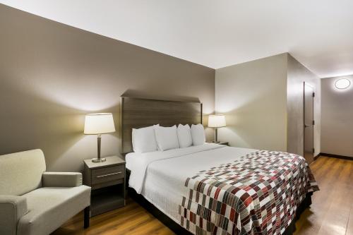 a hotel room with a bed and a chair at Red Roof Inn Denver in Denver