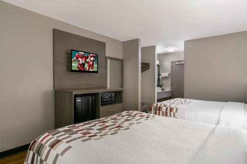 a hotel room with two beds and a tv on the wall at Red Roof Inn Denver in Denver