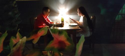 a man and a woman sitting at a table with a cell phone at Pousada La Luna in Paracuru