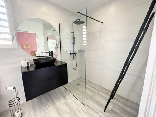 a bathroom with a glass shower with a black sink at Villa PINK in Saint-François