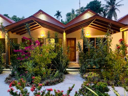 une maison avec des fleurs devant elle dans l'établissement Thoddoo Beach Holiday Inn, à Thoddoo