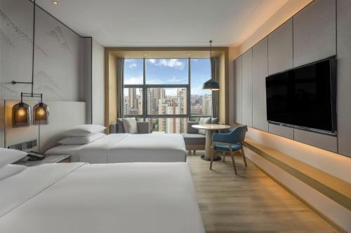 a hotel room with two beds and a flat screen tv at Courtyard by Marriott Foshan Gaoming in Foshan