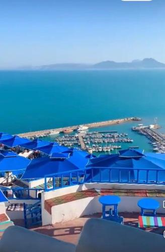 a view of a marina with blue tables and umbrellas at La perle bleue de Sarah in Kheredine