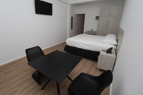 a small room with a bed and a table and chairs at Hotel Royal Brasil in Paramaribo
