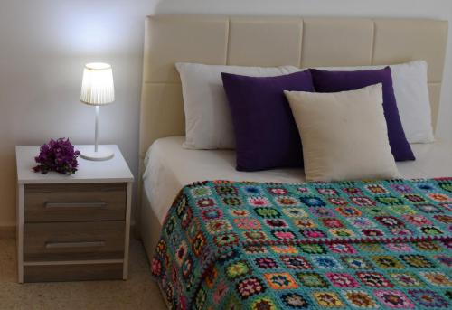 a bed with a colorful blanket and a nightstand with a lamp at Villa Splash in Boğaz