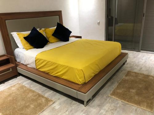 ein Bett mit gelber Decke in einem Schlafzimmer in der Unterkunft Appartement de vacances piscine in Mohammedia