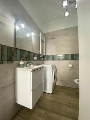 a white bathroom with a washing machine and a sink at Apartament KLIFOWA REWAL przy plaży in Rewal