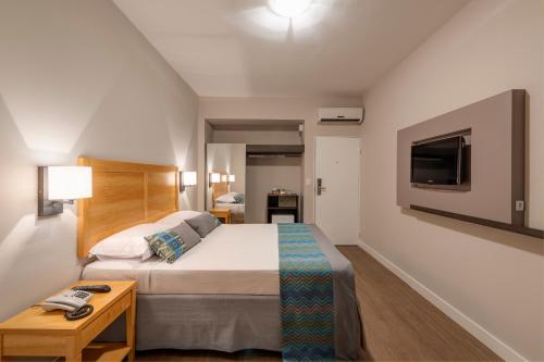 a bedroom with a large bed and a tv at Monreale Express Glicério Campinas in Campinas