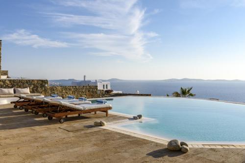 a pool with lounge chairs and the ocean in the background at Villa Yasmina in Tourlos