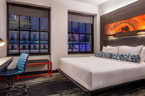 um quarto de hotel com uma cama, uma secretária e janelas em Aloft Philadelphia Downtown em Filadélfia