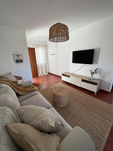 ein Wohnzimmer mit einem Sofa und einem Flachbild-TV in der Unterkunft Coast Beach Apartment - Praia da Areia Branca in Praia da Areia Branca