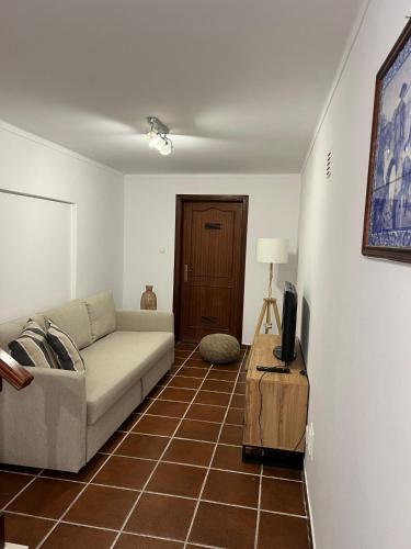 a living room with a couch and a tv at Coast Beach Apartment - Praia da Areia Branca in Praia da Areia Branca