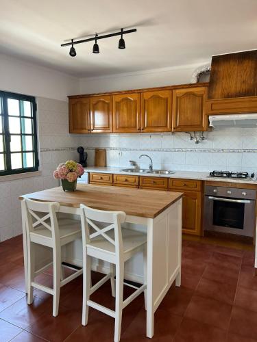 a kitchen with a table and two white chairs at Coast Beach Apartment - Praia da Areia Branca in Praia da Areia Branca